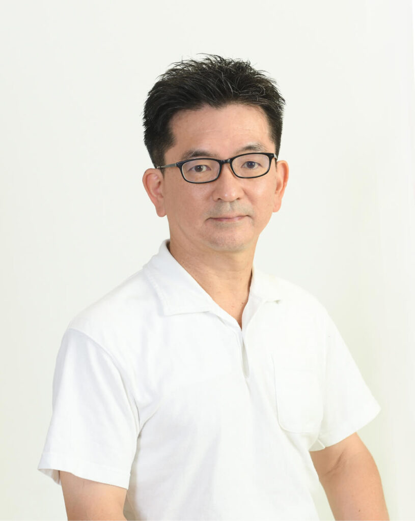 A portrait of a man wearing glasses and a white shirt. He has a serious expression in front of a simple background.